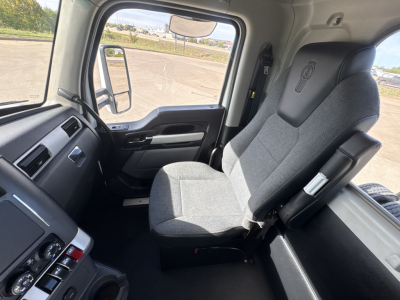 Kenworth T880 cabin interior showing driver's seat and dashboard with window and side mirror.