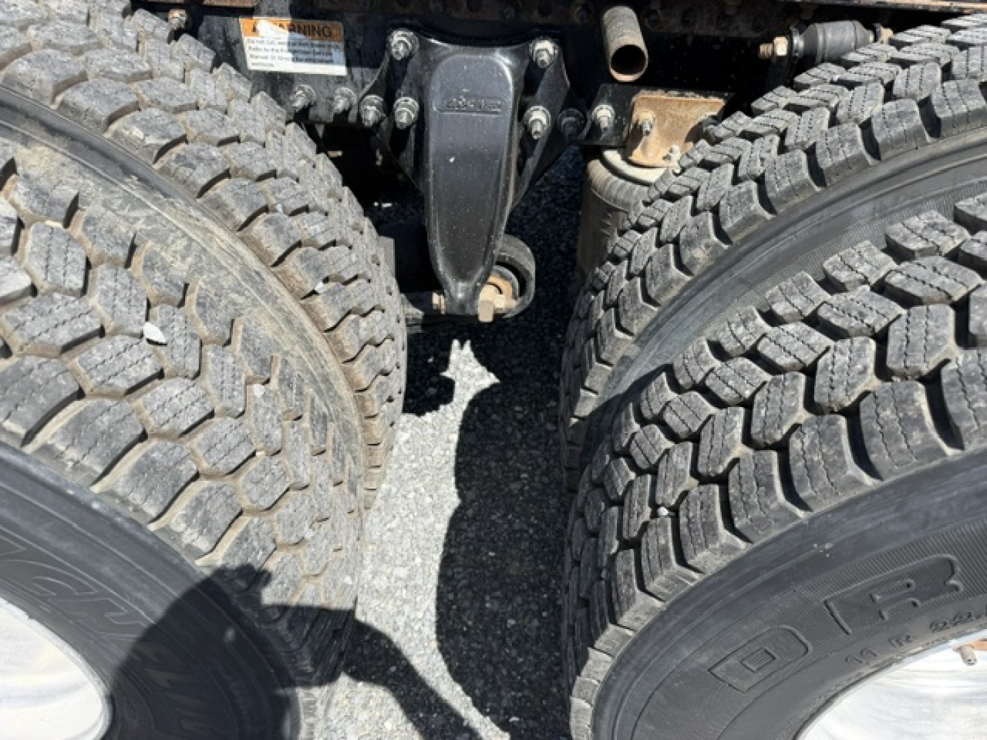 Freightliner Cascadia CA125DC front axle and coupling area showing dual rear wheels and suspension components with tires and drivetrain parts visible.