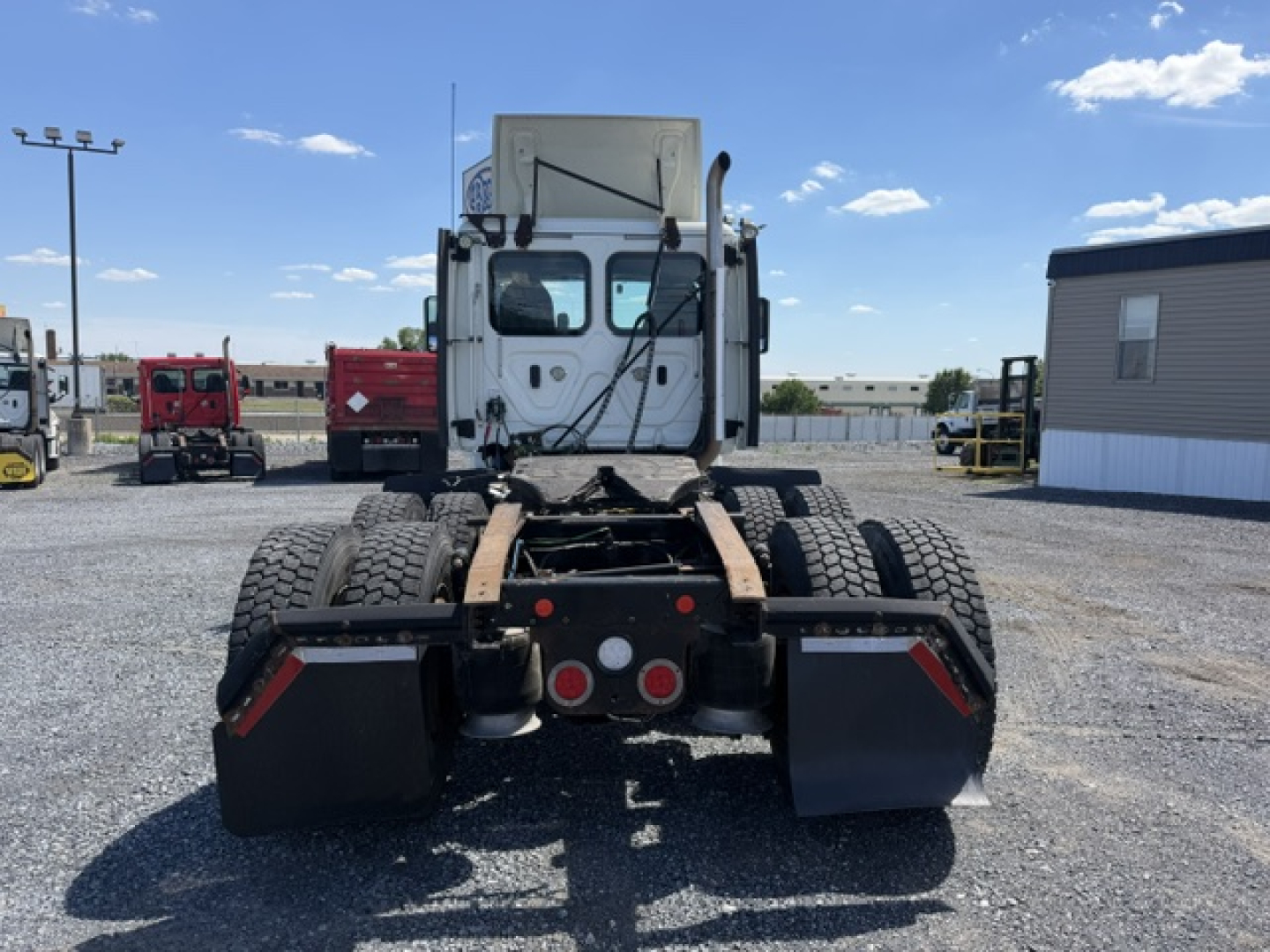 Truck rear view of a 2018 Freightliner Cascadia CA125DC showing dual rear axles and chassis with mud flaps.