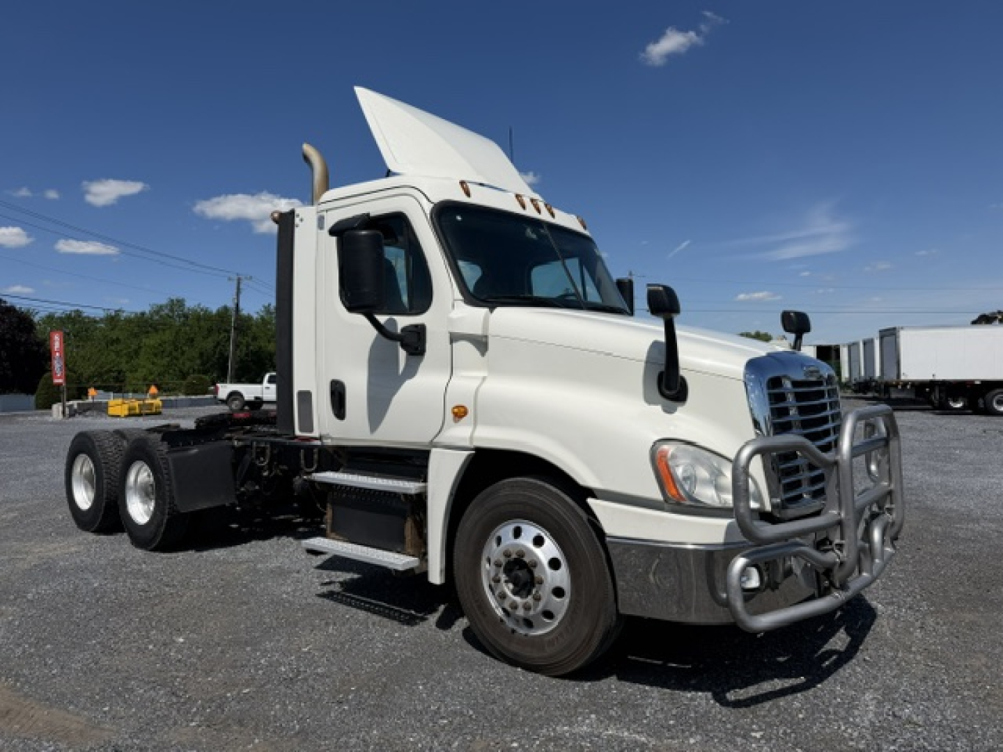 Truck engine bay not visible; Freightliner Cascadia CA125DC side view showing cab and front bumper with grille guard.