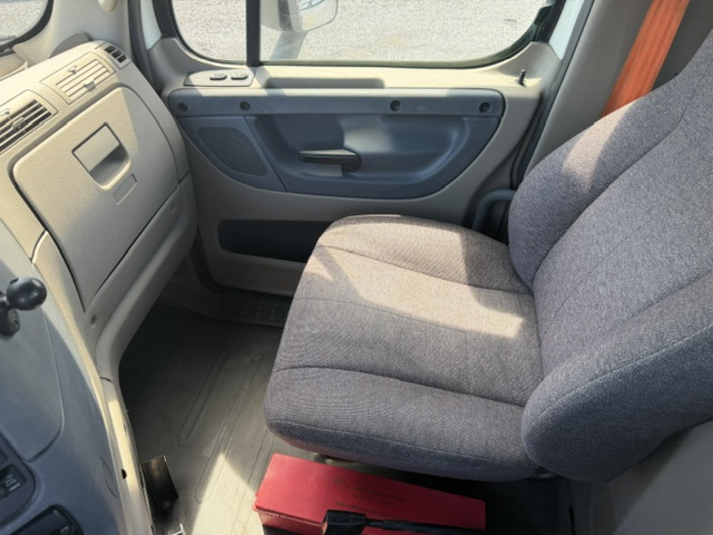 Cab interior view of a Freightliner Cascadia truck showing driver seat and door panel.
