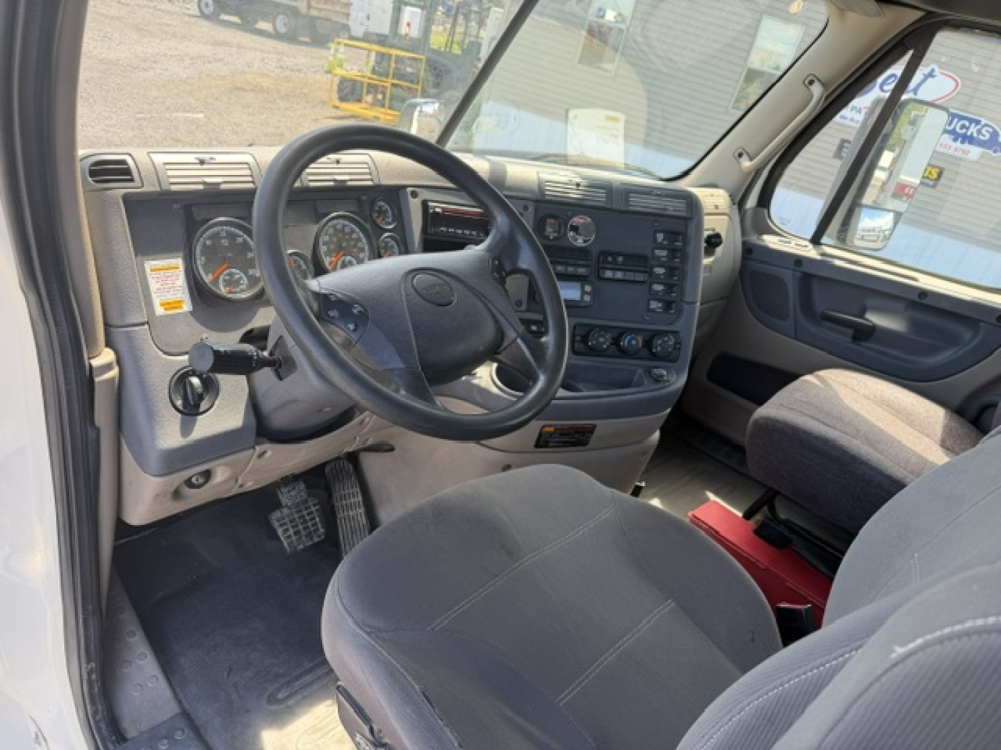 Interior of a Freightliner Cascadia cab showing steering wheel, dashboard gauges, and driver seat.