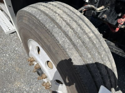 Wheel and tire close-up on Freightliner Cascadia truck showing dual rear wheel hub with lug nuts and tread pattern.