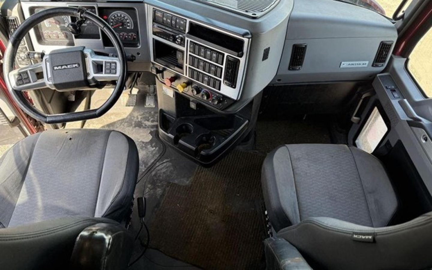 Cab interior of a 2020 Mack Anthem truck showing steering wheel with Mack badge, dash gauges, and two front seats with center console.