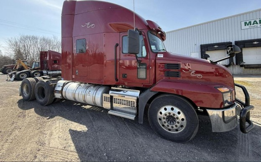 Mack Anthem sleeper tractor shows red cab and chrome fuel tanks with aluminum steps and large front bumper.