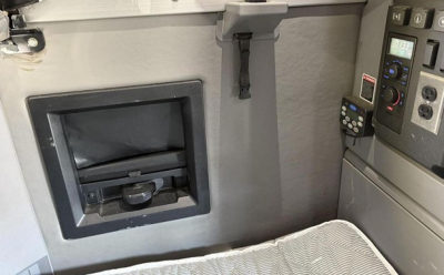 Cab interior of a 2020 Mack Anthem sleeper truck showing a small storage compartment and control panel with switches and a manual window latch.