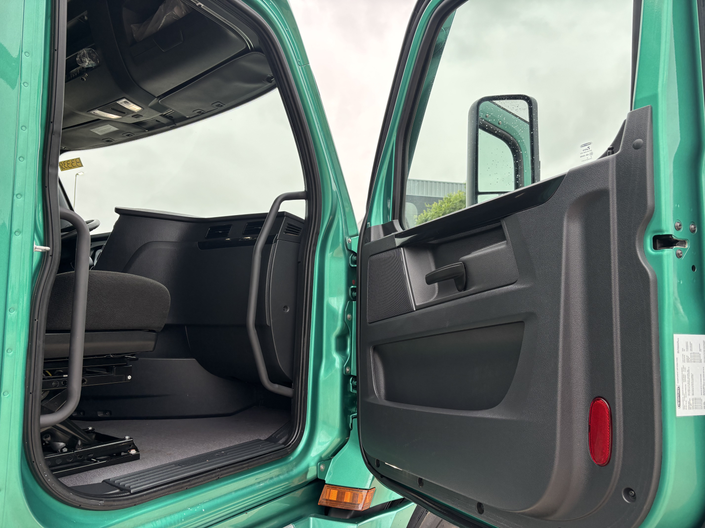 Cabin entry of a Freightliner Cascadia 126 truck showing front door open and interior seating visible.