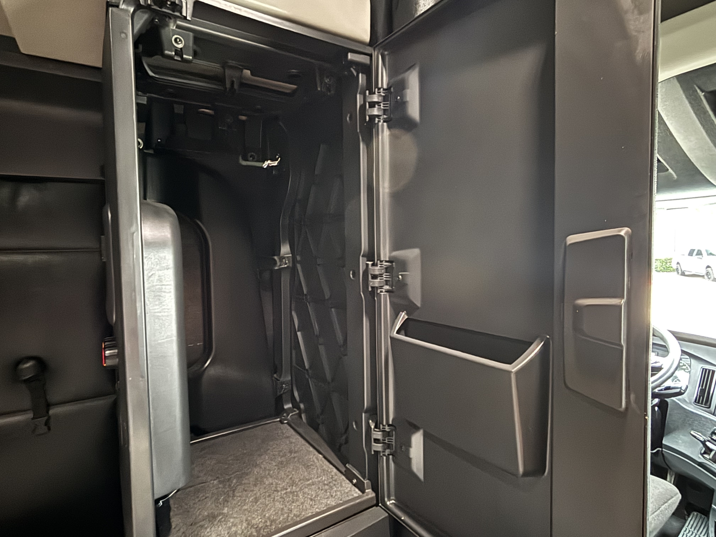 Truck cab interior storage compartment open door showing shelves and molded pockets; Freightliner Cascadia 126 dash area visible outside.