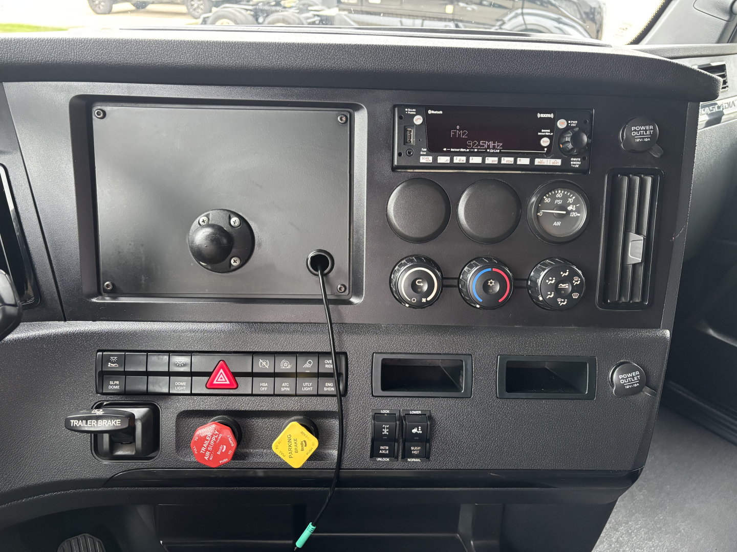 Dashboard view of a 2023 Freightliner Cascadia 126 truck showing instrument cluster, climate controls, radio, hazard switch, and various switches.