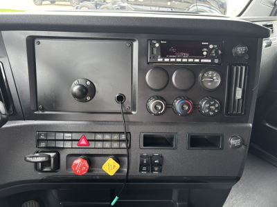 Dashboard view of a 2023 Freightliner Cascadia 126 truck showing instrument cluster, climate controls, radio, hazard switch, and various switches.