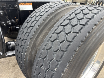 Rear dual tandem tires of a Freightliner Cascadia 126 tractor-trailer showing tread pattern and wheel well.