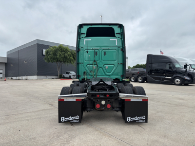 Truck chassis rear view with green cab and dual mud flaps showing Bruchner's logo at trailer connection area.