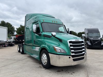Freightliner Cascadia 126 cab with green paint, front grille, chrome bumper, and side mirrors in view.