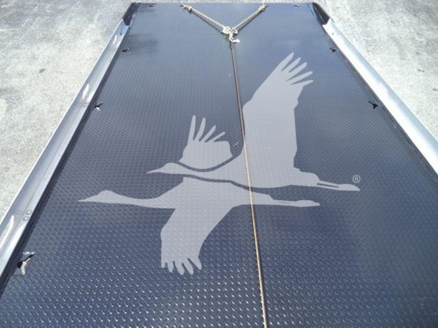 Flatbed with diamond plate surface showing a large bird logo and a chain across the center.