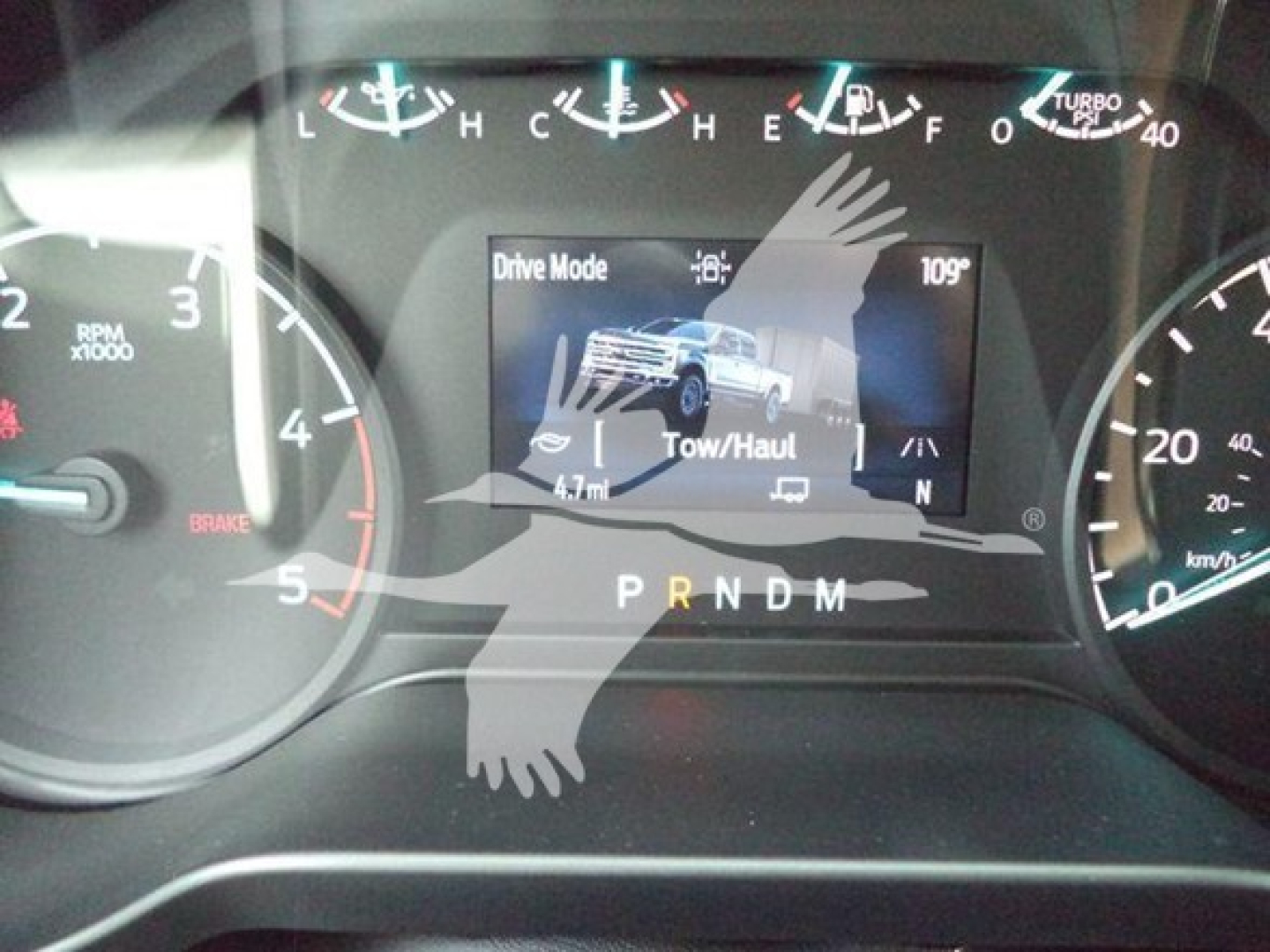 Dashboard view of a 2024 Ford F-550 instrument cluster showing Drive Mode and Tow/Haul screen, gear indicator PRNDM, and analog gauges.