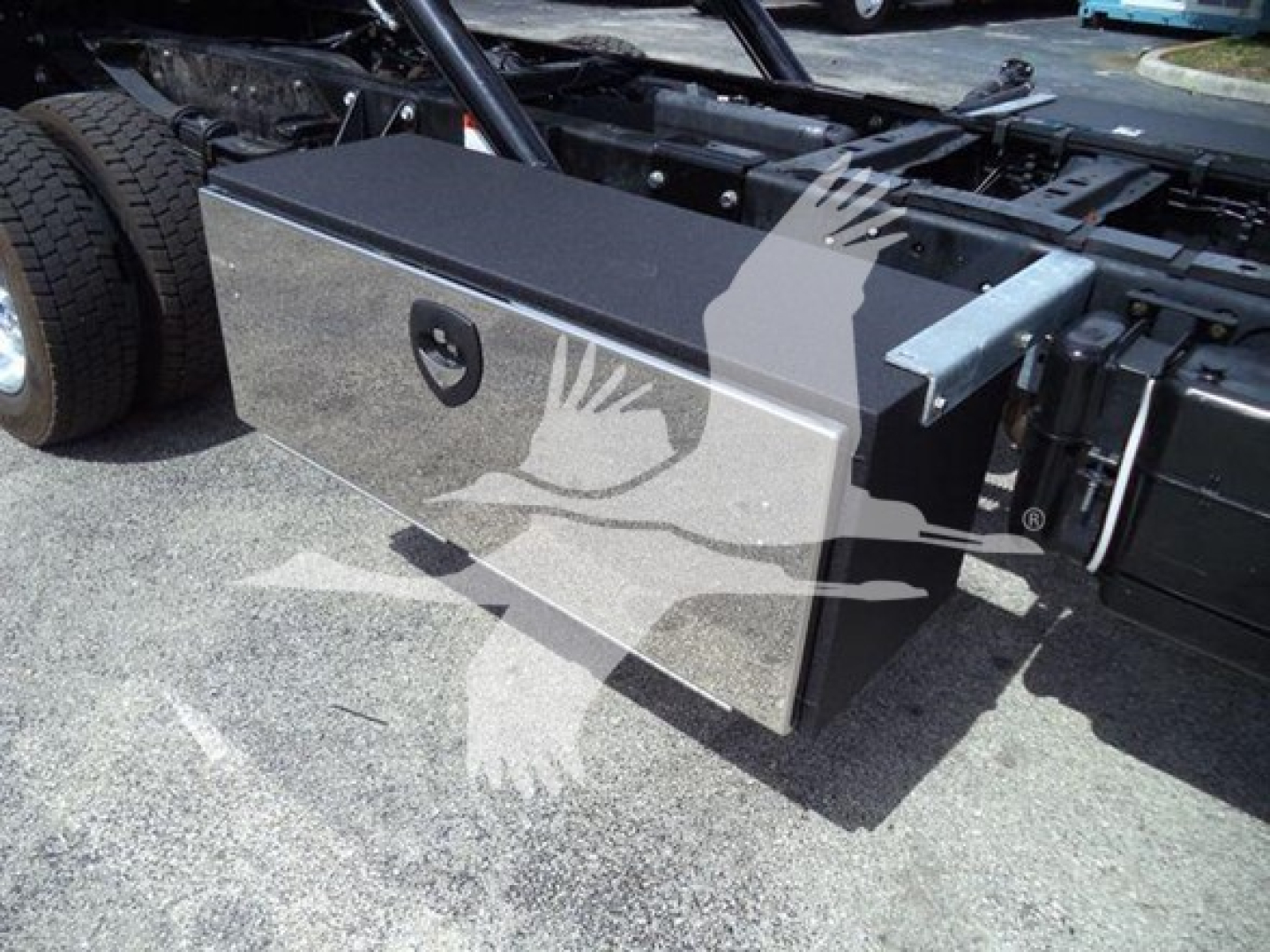 Ford F-550 rollback truck chassis with a large rectangular toolbox mounted on the side undercarriage and fuel/air lines visible.