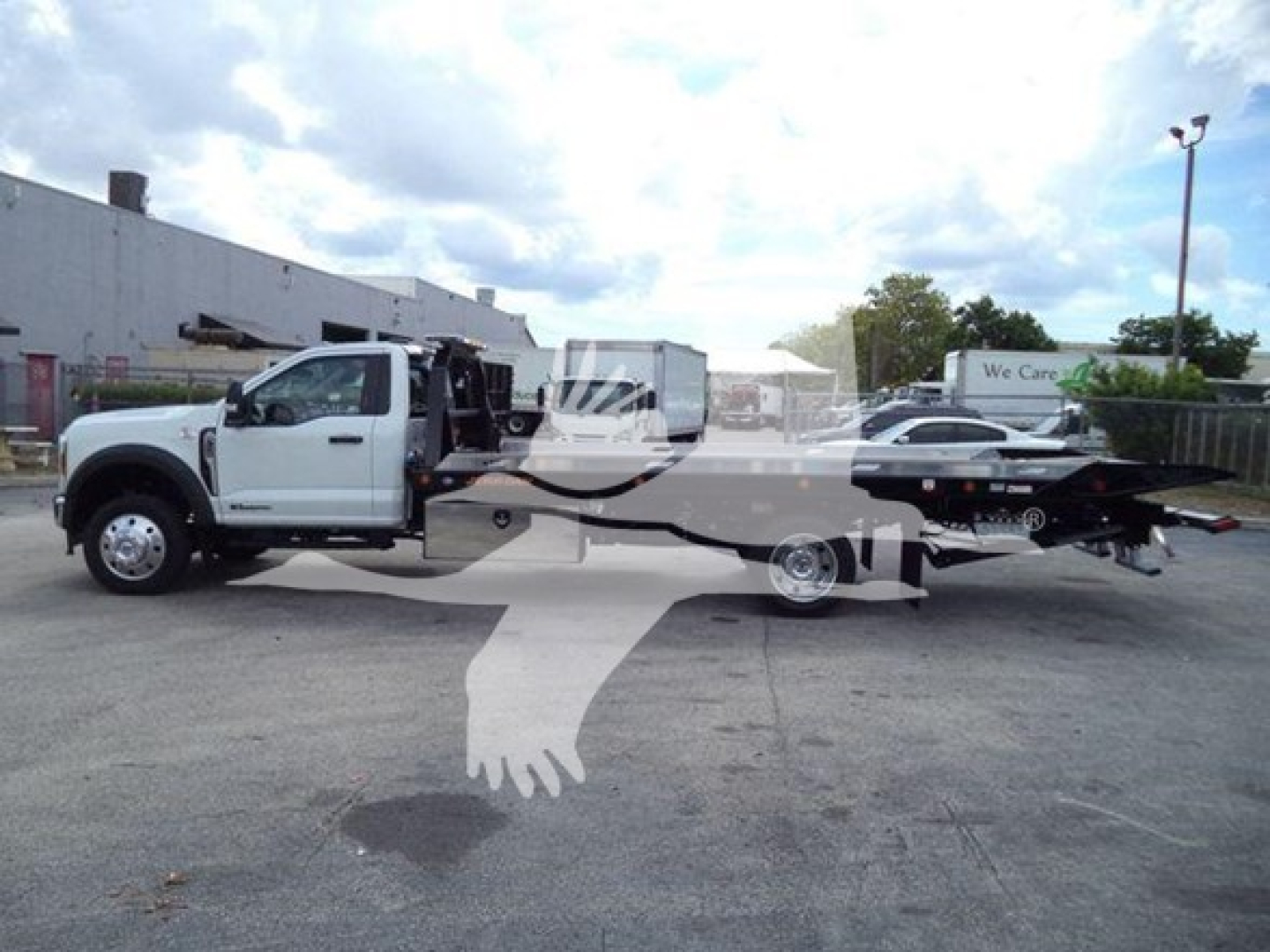 Ford F-550 tow truck in side view with a rollback bed, front cab visible on left and flatbed extending to right.