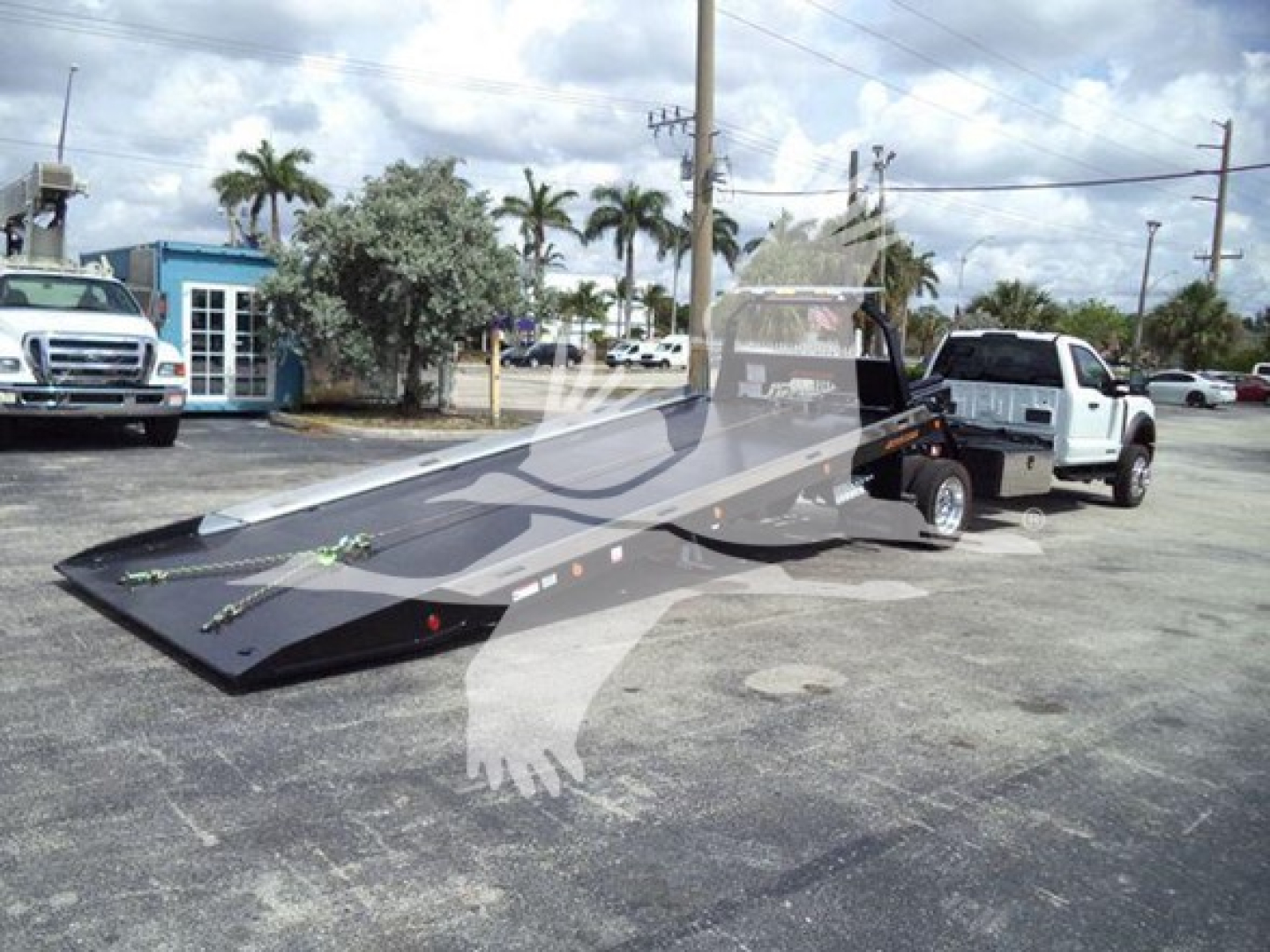 Ford F-550 rollback tow truck with a long flatbed ramp extended, white cab, loading ramp and towing equipment visible.