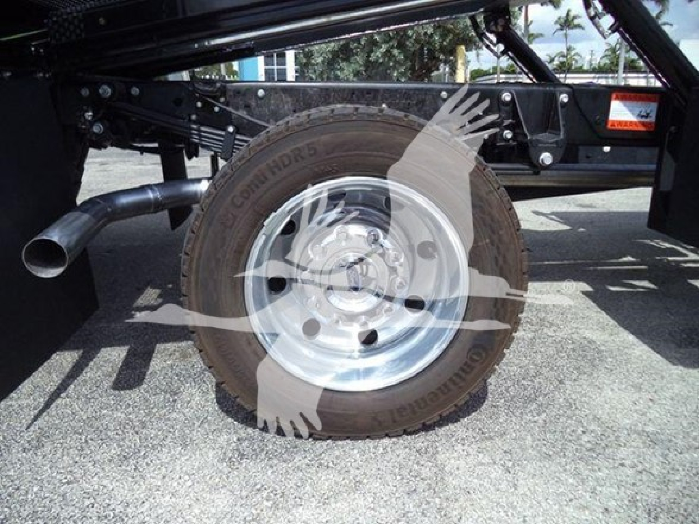 Ford F-550 rollback truck wheel and tire visible with spare wheel hub, undercarriage frame, and hydraulic components.