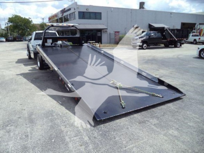 Ford F-550 rollback tow truck with flatbed in lowered position and hydraulic winch area visible.
