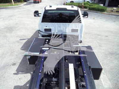 Ford F-550 rollback truck front view with flatbed equipment and hydraulic chassis in foreground.