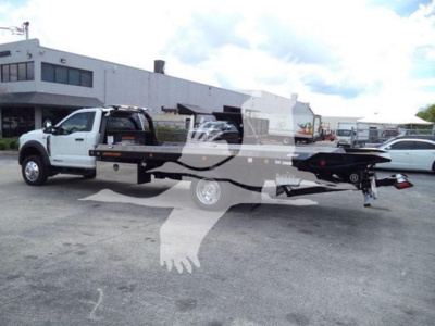 Ford F-550 rollback tow truck in a parking lot showing a flatbed withRamp and branding on side.