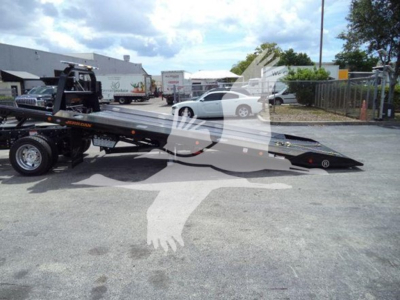 Ford F-550 rollback tow truck with a lowered flatbed; visible lettering on the bed and equipment, no legible serials or stickers readable from this angle.