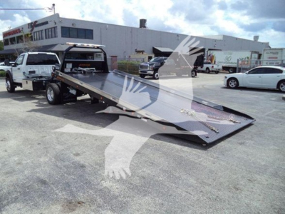 Ford F-550 rollback truck with ramp bed shown in a dealership lot