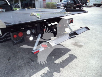 Ford F-550 rollback truck rear view showing hydraulic tiller and steel platform with steps and safety chains.
