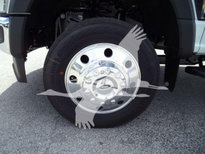 Ford F-550 wheel and tire assembly visible in front of a rollback truck with chrome hubcap and lug nuts.