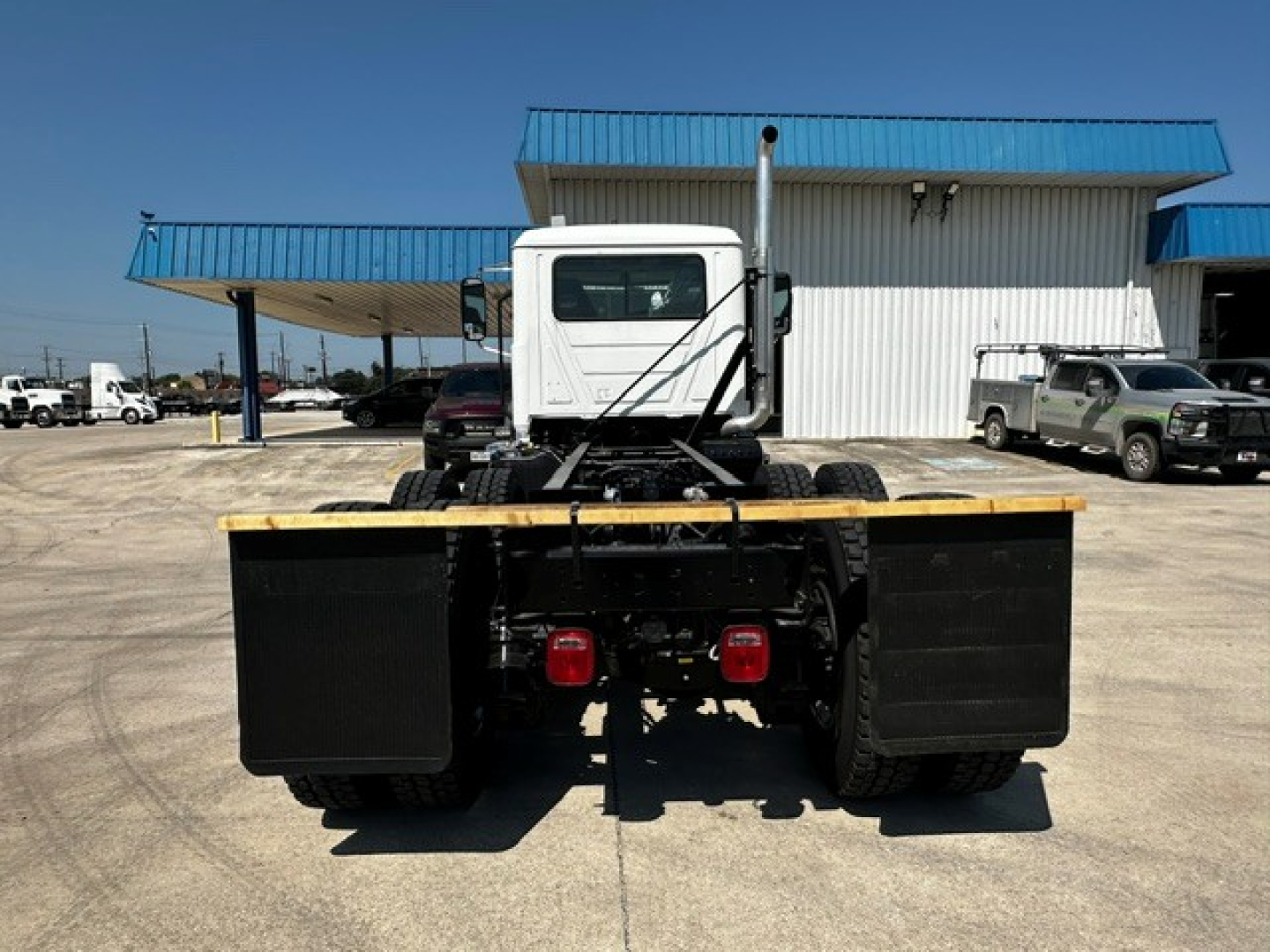 Mack GR64F cab and chassis rear view showing dual rear wheels, heavy-duty frame, and rear mud flaps.