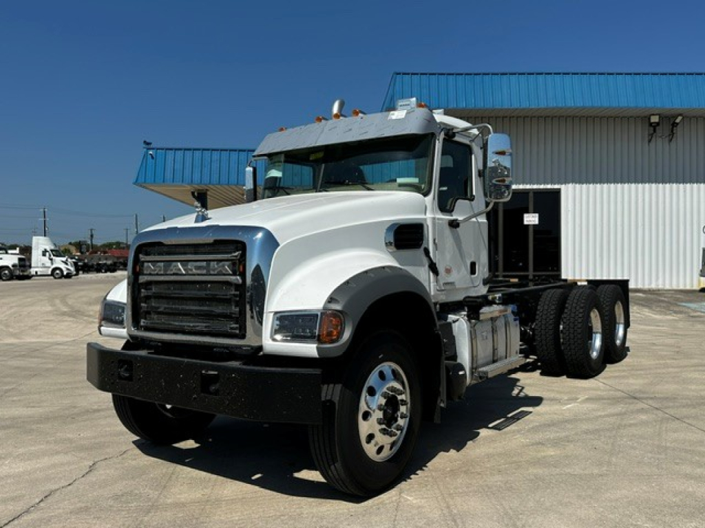 Truck cab and chassis showing Mack GR64F front, two-axle cab, chrome exhaust stack, big black front bumper. Visible text on grille area indicates 'MACK' badge.