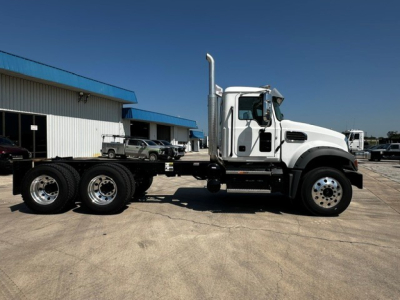 Mack GR64F cab and chassis truck side view showing white cab, dual rear axles, and silver exhaust stack.