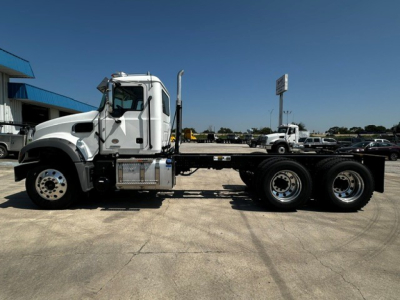 Truck chassis side view showing Mack GR64F cab and chassis with dual rear axles, chrome fuel tanks, and step; no visible text on side panels.