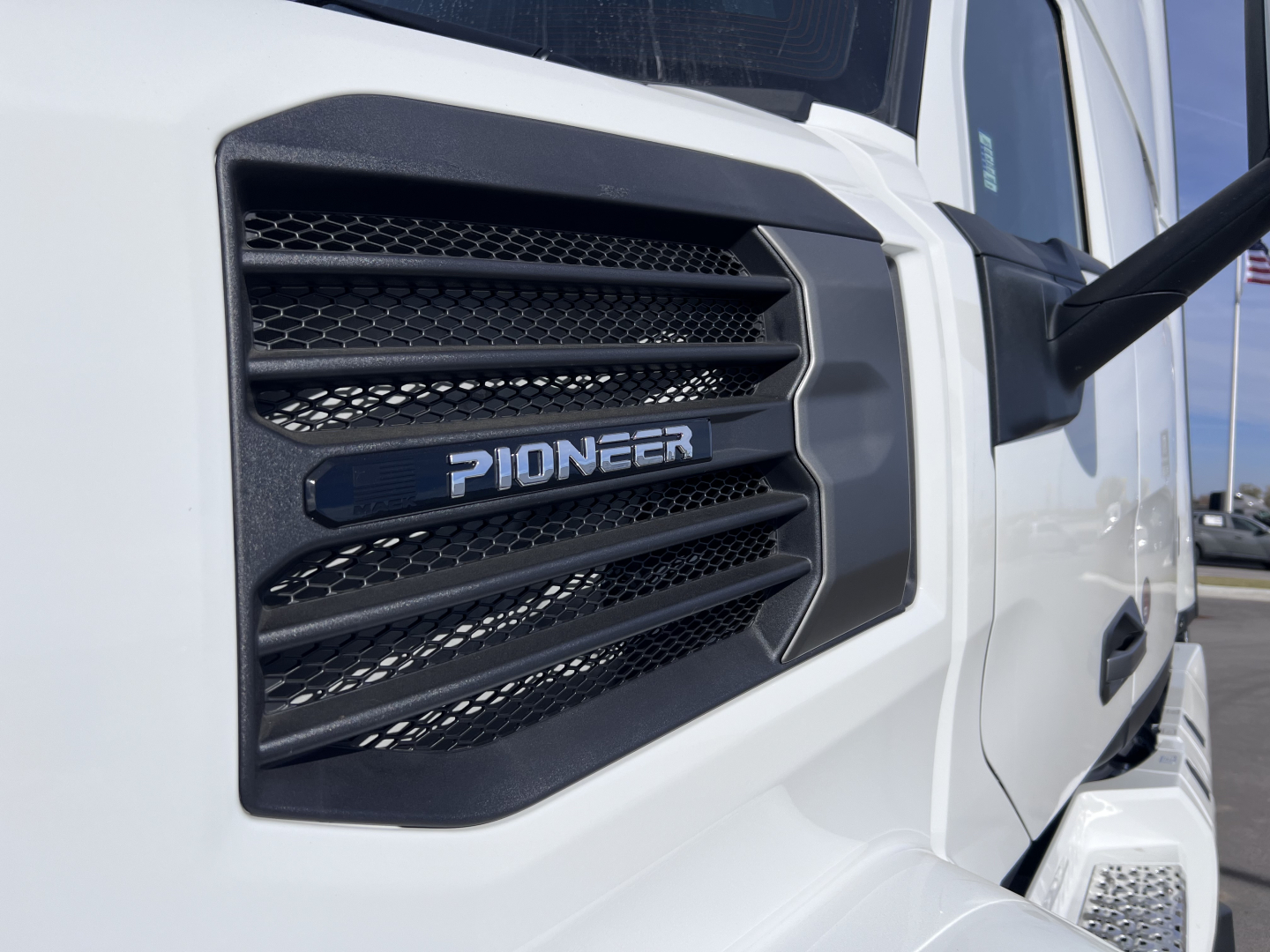 Pioneer engine badge on Mack PR64T76H truck cab side vent, close-up view showing grille and hood area.