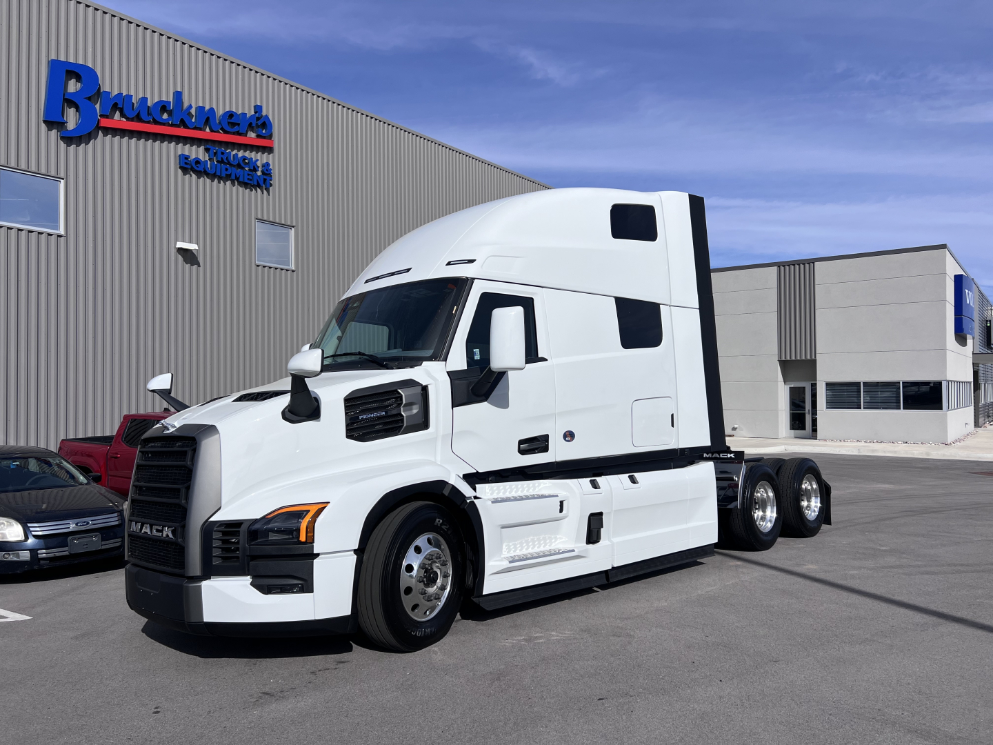 Mack PR64T76H tractor-trailer truck parked outside a dealership.