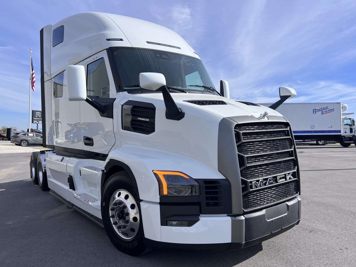 Mack PR64T76H conventional sleeper truck in white, front three-quarter view, showing large black grille, cab, and side mirrors.