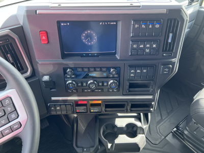 Cab interior of a 2026 Mack PR64T76H showing dashboard with digital instrument cluster, climate controls, and storage/cup holders.