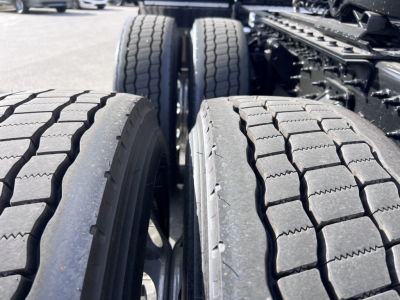Mack PR64T76H truck tandem axles with dual rear tires and tread detail visible, wheel rims and chassis components in background.