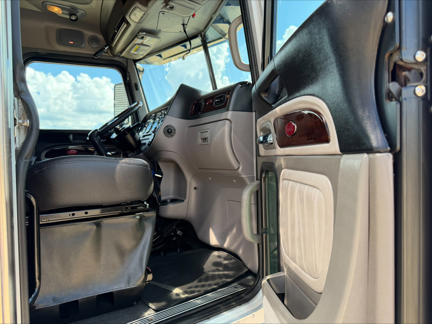 Truck cab interior view showing driver's seat and dashboard from open door; visible text includes no explicit branding in image.