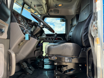 Peterbilt 389 truck interior cab view showing steering wheel, dashboard, and driver seat with controls.