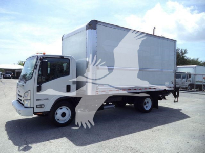 Isuzu NPR-HD box truck in a used status with a large box cargo area; cab shows Isuzu badge and front grille, surrounding lot with other similar trucks.