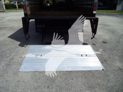 Isuzu NPR HD truck with lowered aluminum ramp extending from back, rear view showing platform area and tailgate latches.