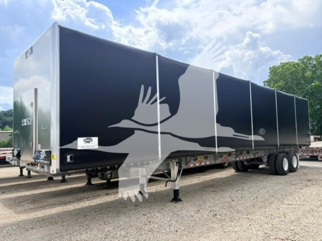 Trailer side showing large graphic of a hand and bird on a dark galvanized steel flatbed curtain side trailer. Side panel text not fully legible; some white stickers near rear.
