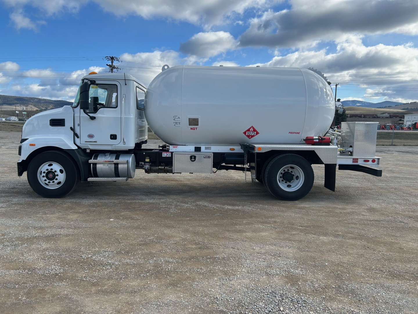 Side view of a white 2026 Mack MD7 tanker truck showing cylindrical tank and chassis with front cab and dual rear wheels.
