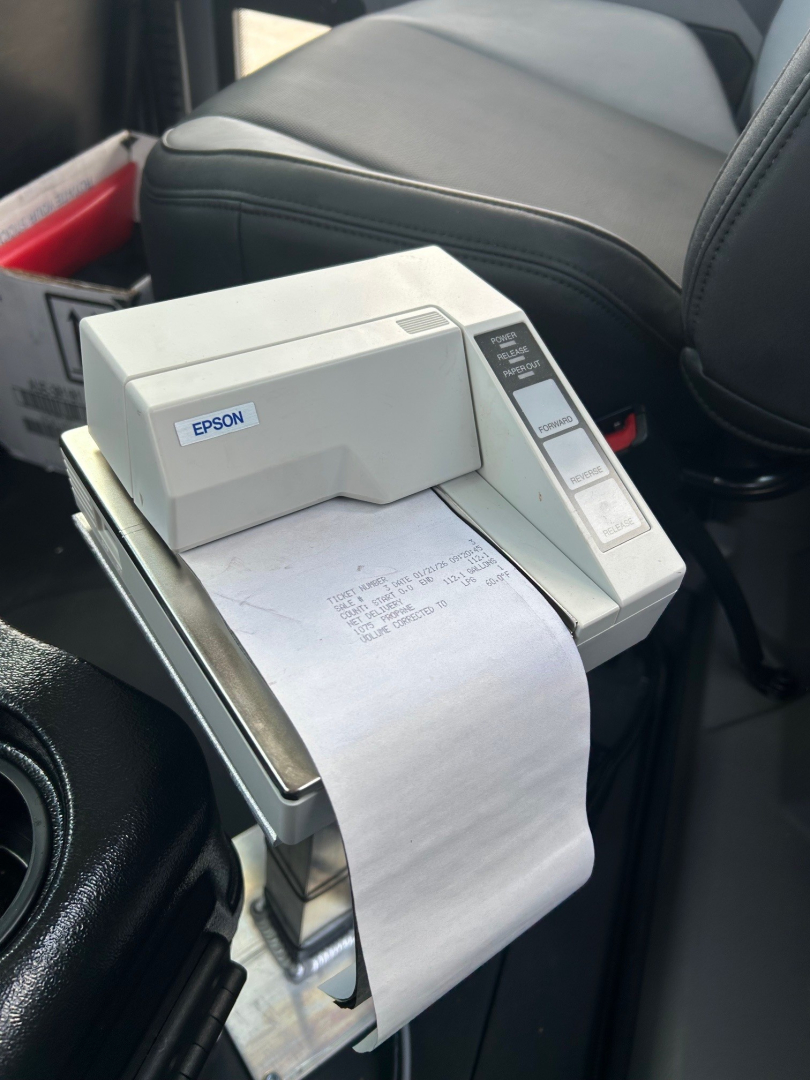 Printer labeled Epson mounted in a truck cabin with a receipt paper feed visible.