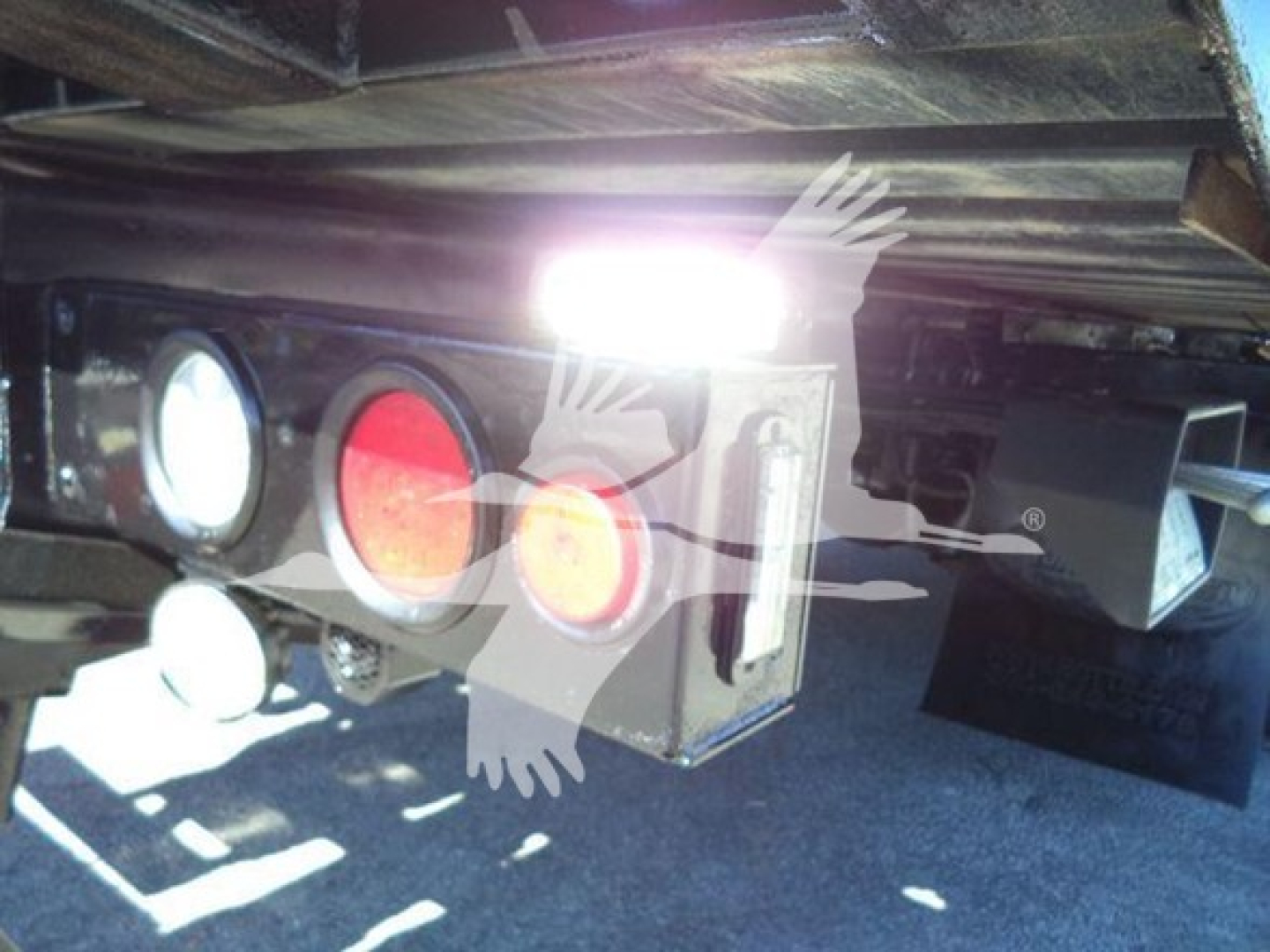Truck hitch area showing rear lights and hitch components under plyboard bed