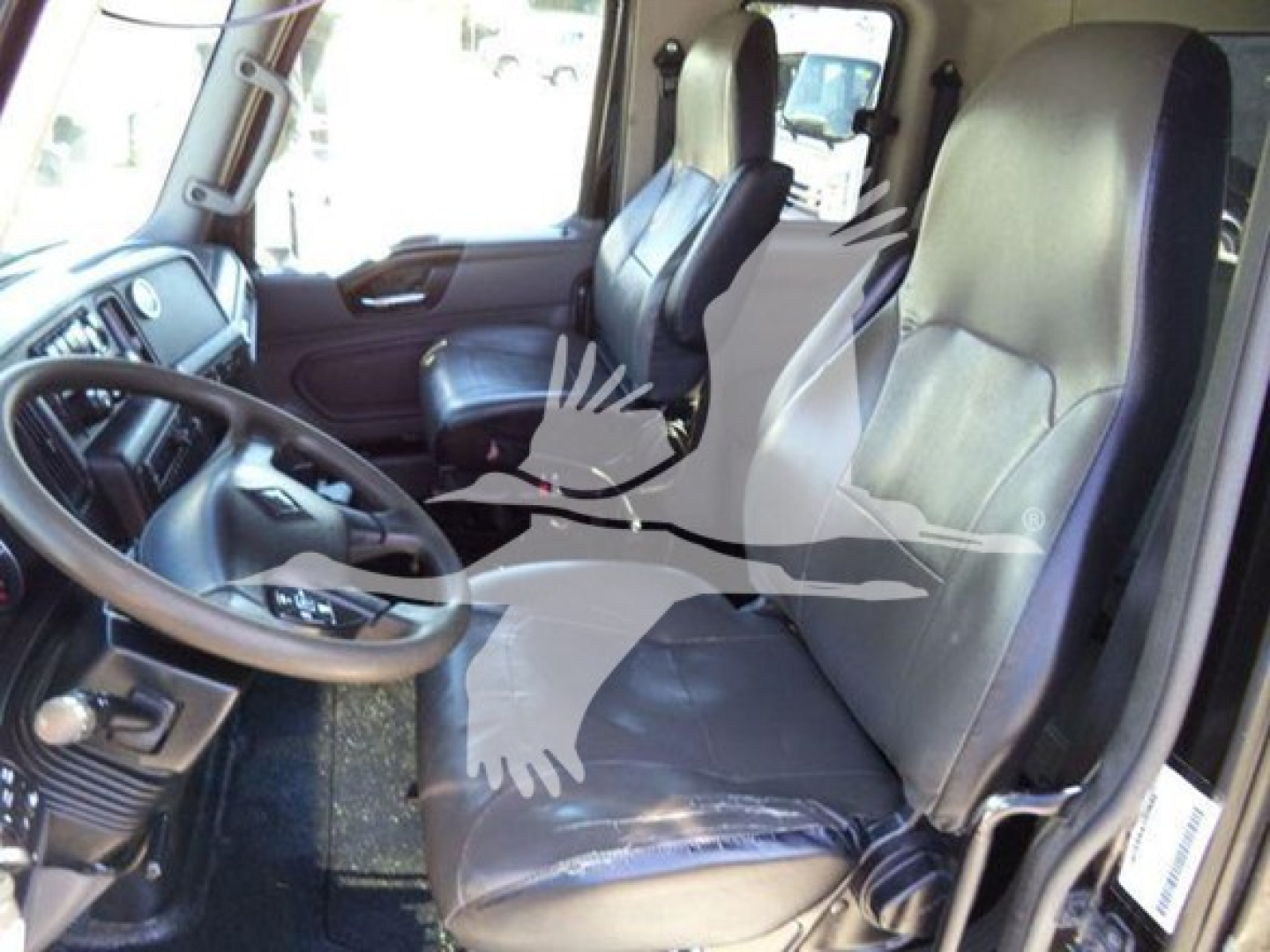 Truck cab interior showing steering wheel and two front seats in a manual transmission truck.