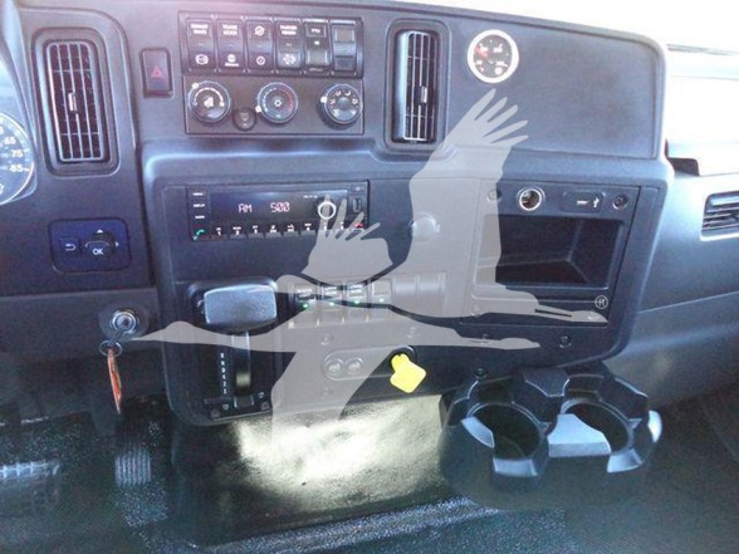 Interior of a 2022 International MV cab showing dashboard with climate controls, radio, cup holders, and a yellow tag near the center; VIN and stock info not visible in text.