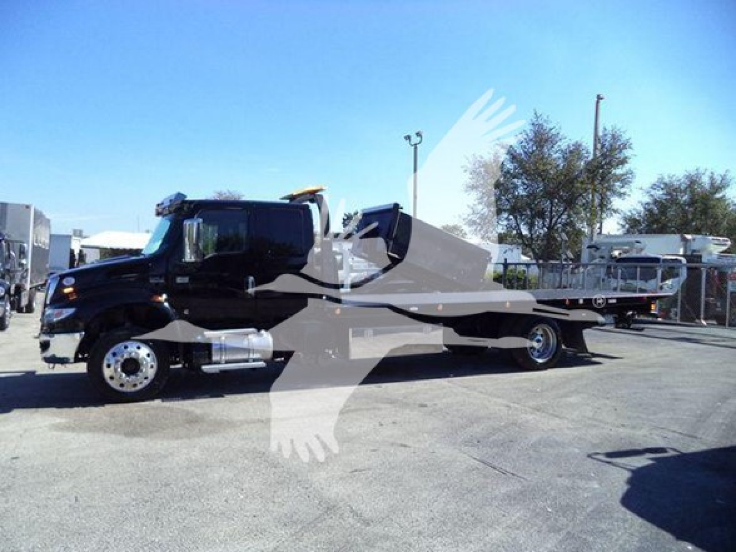 2022 International MV rollback truck in a lot showing side view with long flatbed and black cab.